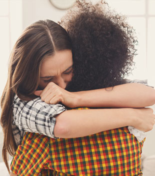 sisters in flannel shirts hugging and are upset. image for cancer support for families