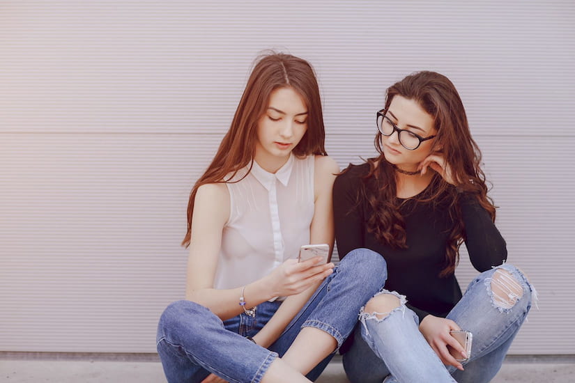 Siblings talking and looking at phone