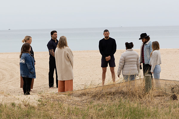 a group of young people standing in a circle at the beach for canteen's national reconciliation week
