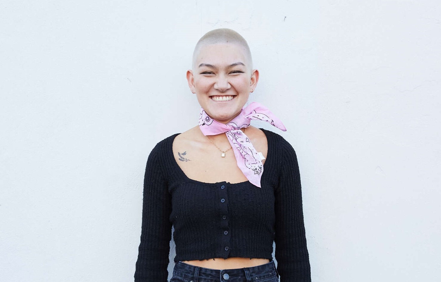 young person with short hair standing and smiling at the camera