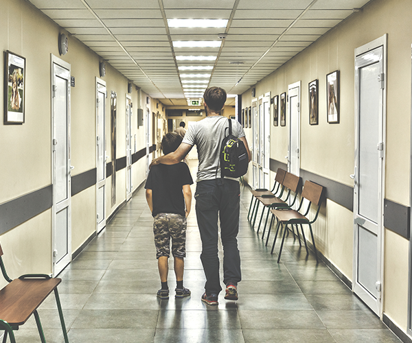 Father and Son walking down a hospital cancer ward corridor - image for young adult cancer and youth cancer services