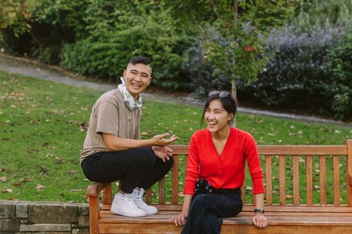two young people sitting on a park bench together
