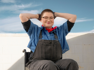 Happy young person with hands on head, supported by Canteen, a good charity to donate to in Australia.