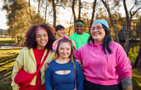 group of young people smiling and wearing Canteen bandannas, supporting one of the best charities to donate to in Australia.