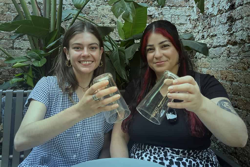 two friends holding upside down glasses for dry july