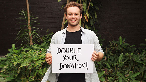 image of james holding a sign saying double your donations