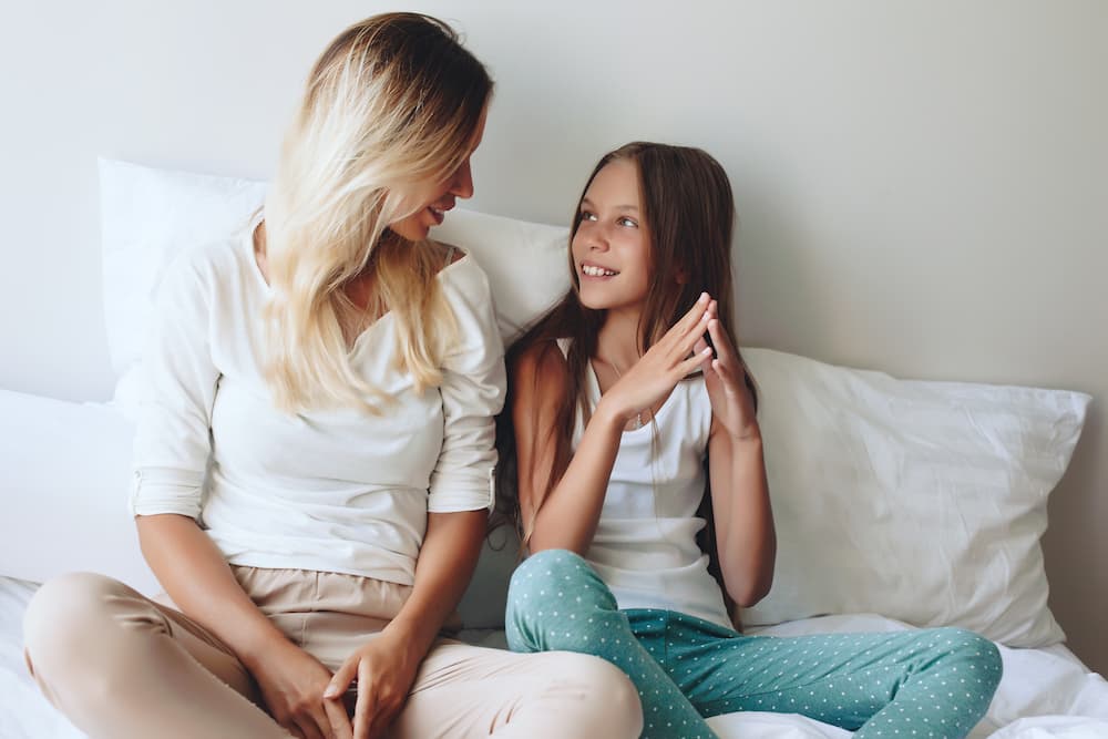 mother and daughter talking on bed