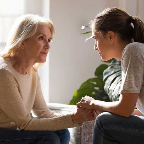 Young woman speaking with her mother about cancer