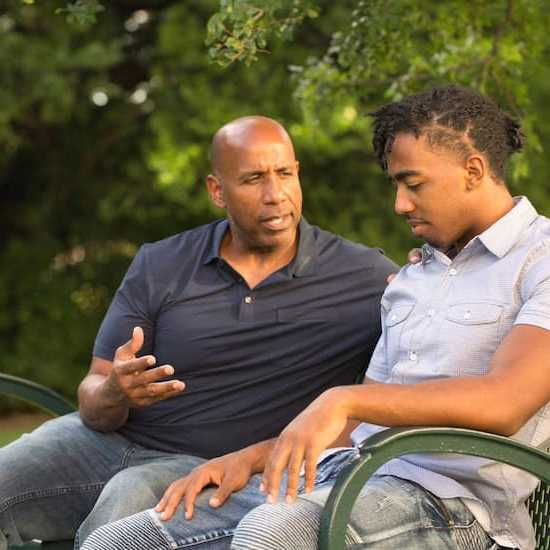 Father and son discussing cancer in a park