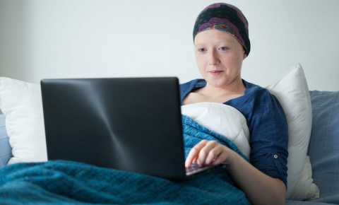 Young woman in hospital bed doing school work