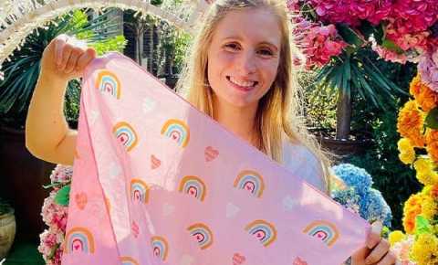 Person holding Valentine's day bandanna in front of a heart shaped flower arrangement