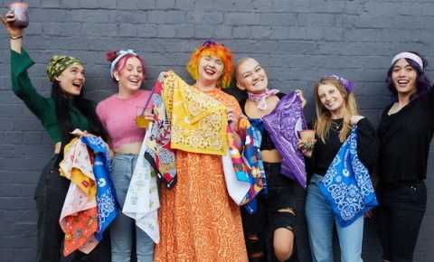 six canteen volunteers wearing canteen bandannas and shirts. they are laughing together