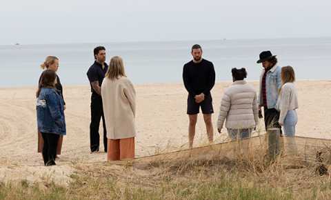 a group of young people standing in a circle at the beach for canteen's national reconciliation week