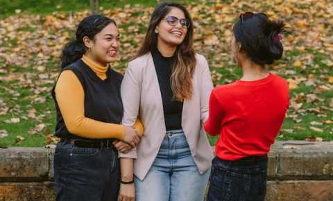 three young people laughing and having a conversation 