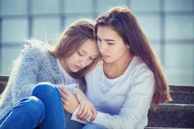 young person hugging and comforting their friend who has cancer