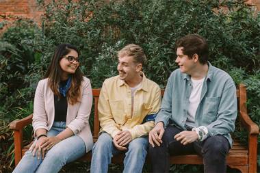 Three people sitting in the park talking