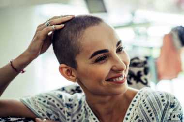 young person with cancer is looking to the side and smiling