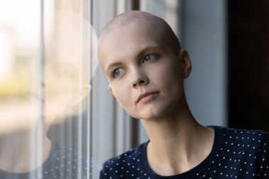 young person impacted by cancer leaning on a window