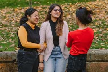 three young people laughing and having a conversation 