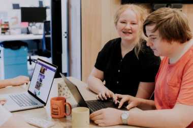 A young girl and young boy working on laptops at a table 