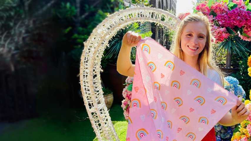 Person holding Valentine's day bandanna in front of a heart shaped flower arrangement