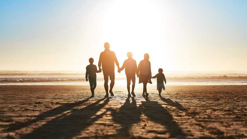 family of 5 walking on the beach together