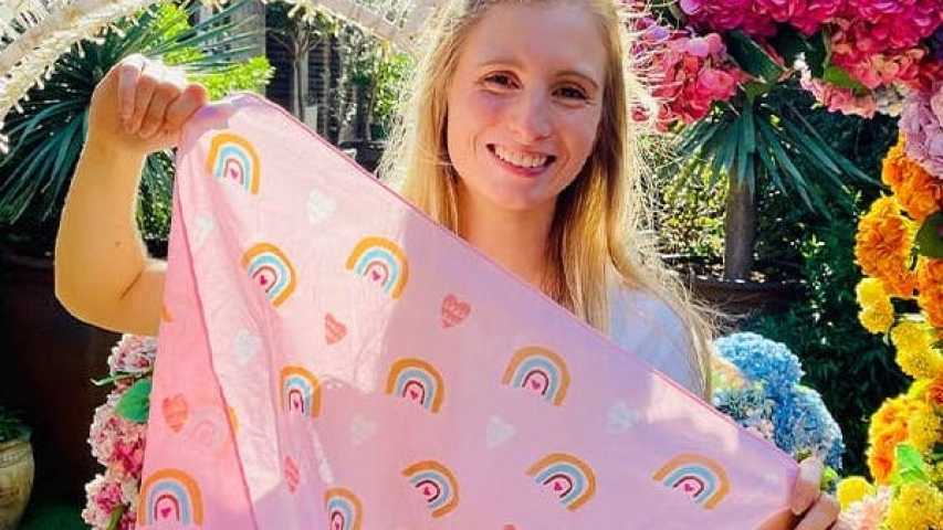 Person holding Valentine's day bandanna in front of a heart shaped flower arrangement