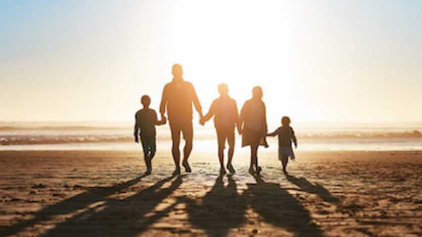 family of 5 walking on the beach together