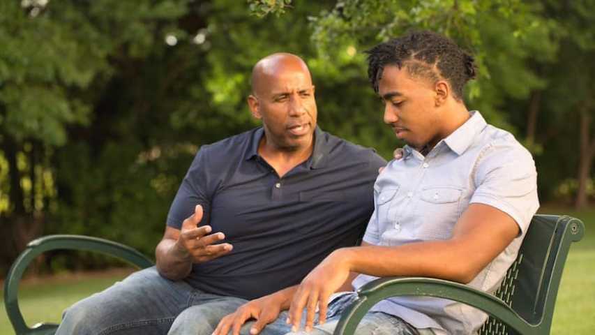 Father and son discussing cancer in a park