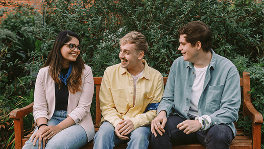 Three people sitting in the park talking