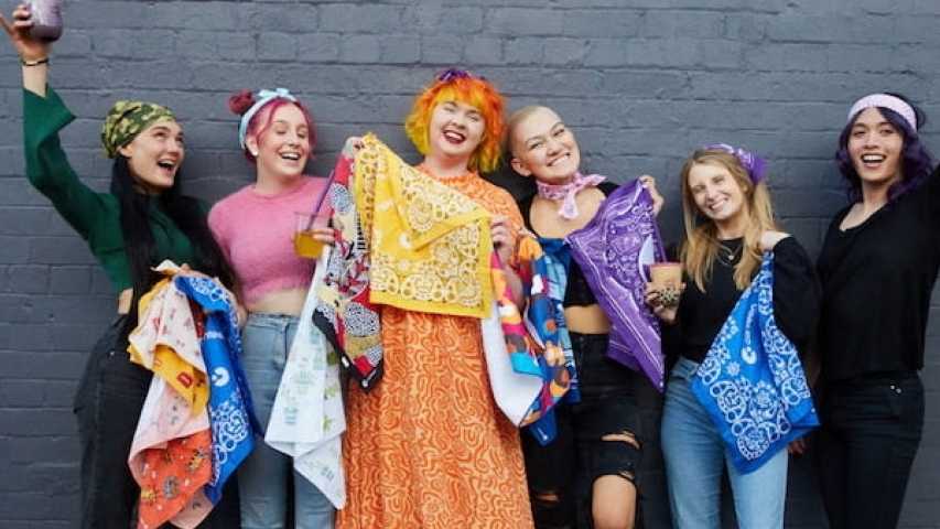 six canteen volunteers wearing canteen bandannas and shirts. they are laughing together