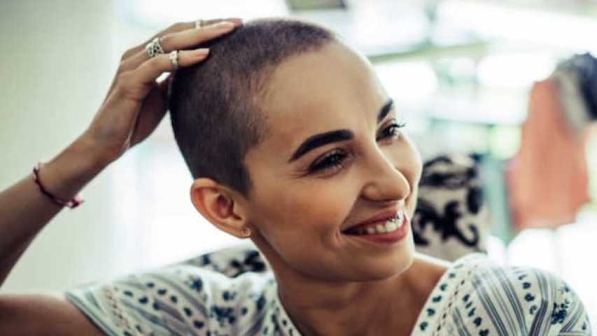 young person with cancer is looking to the side and smiling