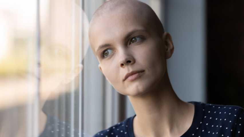 young person impacted by cancer leaning on a window