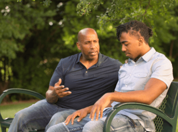 Father and son discussing cancer in a park