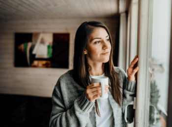 Young woman holding cup looking out window