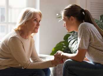 Young woman speaking with her mother about cancer