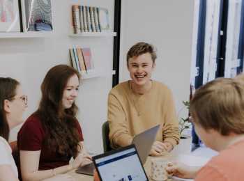 group of young people impacted by cancer smiling around a table