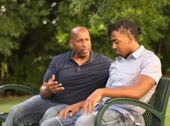 Father and son discussing cancer in a park