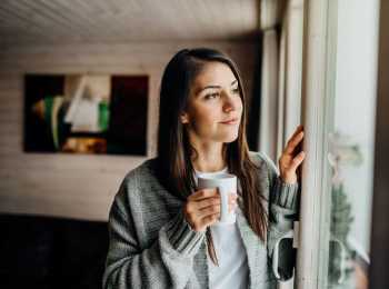 Young woman holding cup looking out window