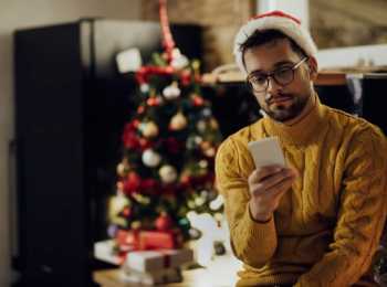 young person wearing a santa hat and looking at their phone
